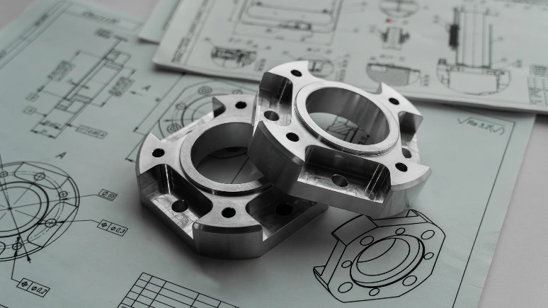 Two metal mechanical parts on engineering blueprints